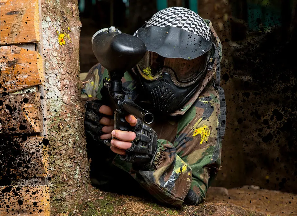 A man in camouflage holding a paintball gun.